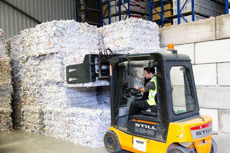 Bales of paper being stacked into piles